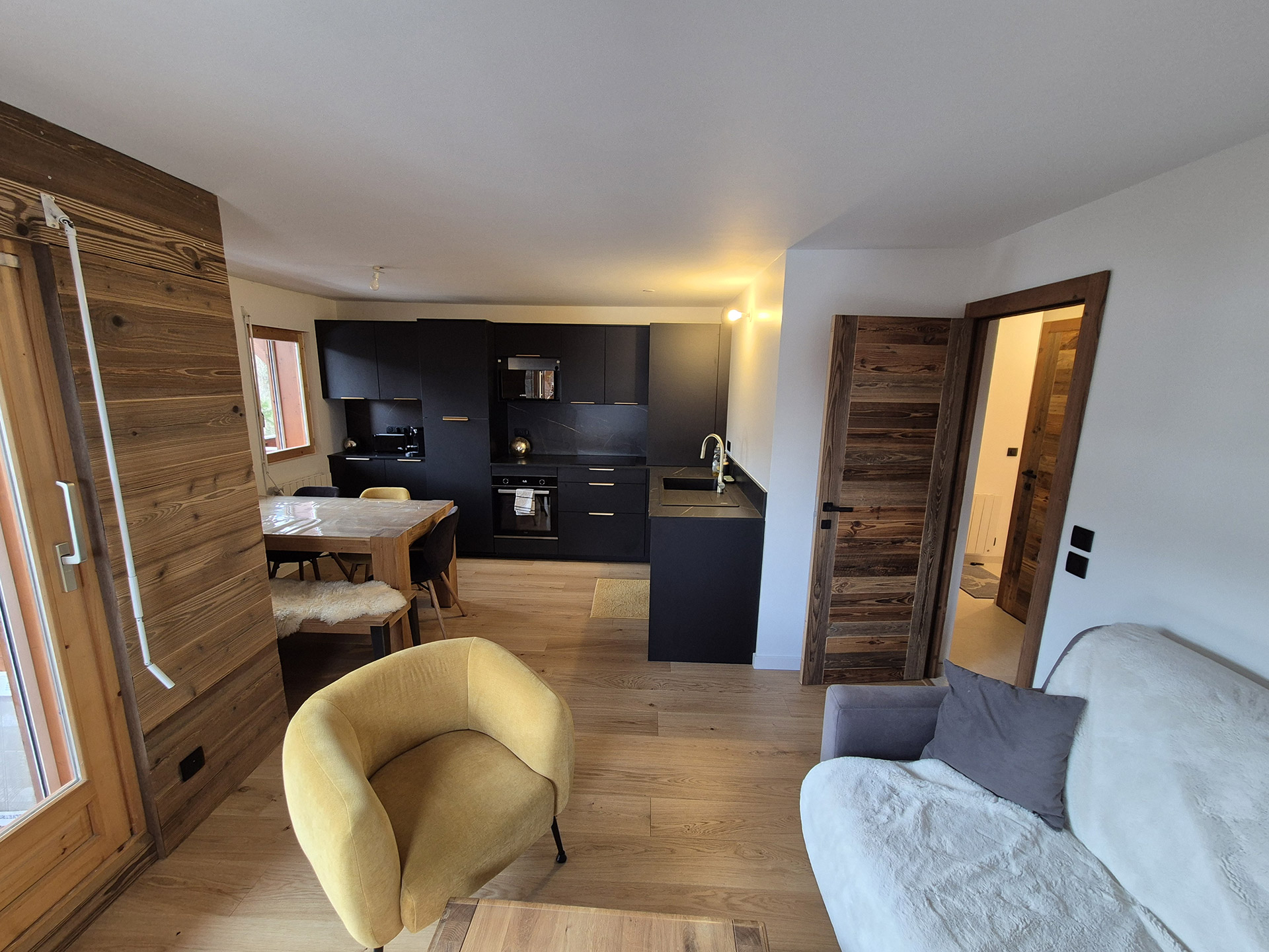 Cuisine ouverte et salon rénovés dans un appartement de montagne en Haute-Savoie avec parquet et aménagement sur mesure