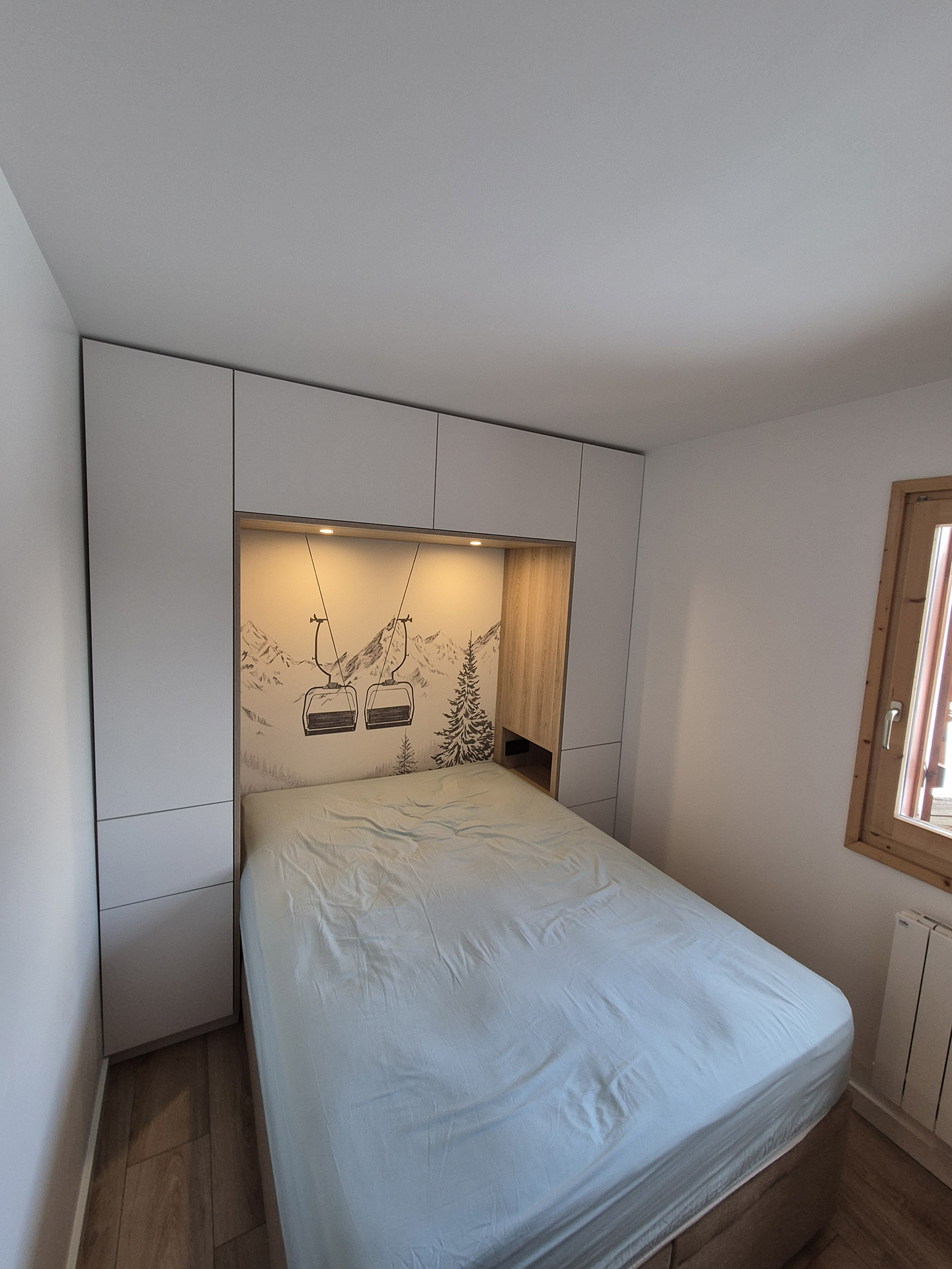 Chambre avec lit intégré et rangements sur mesure dans un appartement rénové en Haute-Savoie